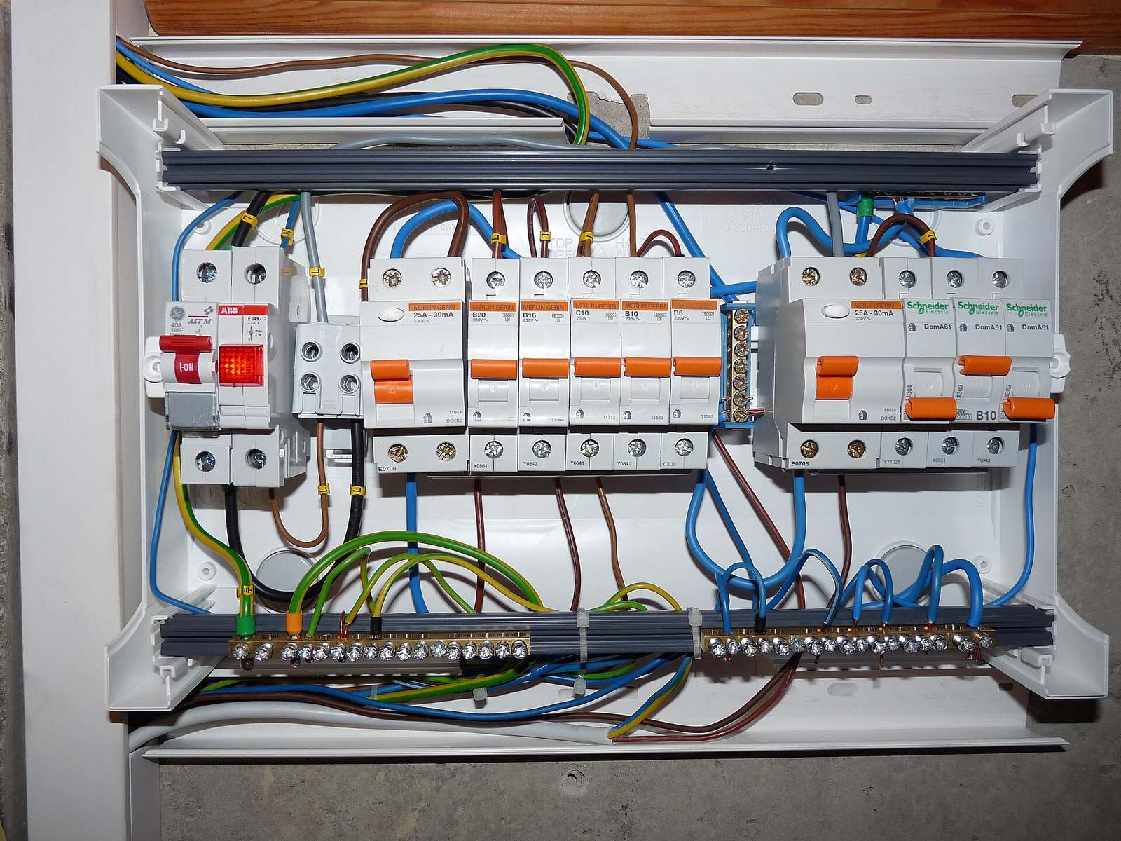 Geopende elektrische verdeelkast met een rij automaten, differentieelschakelaars en gekleurde bedrading